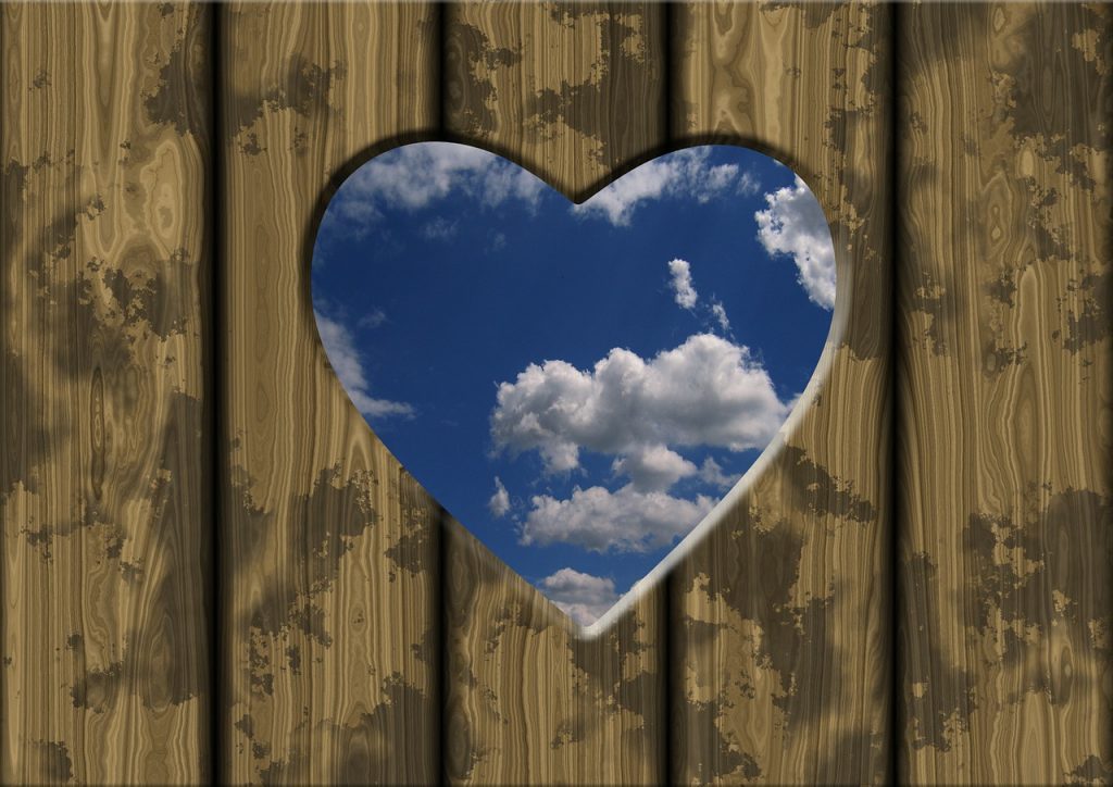 Eine Tür mit einem Herz durch das man den blauen Himmel sieht