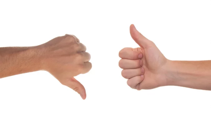 Zwei Hände, die einen Gaumen hoch und einen Daumen runter zeigen. En Symbol für Entscheidung